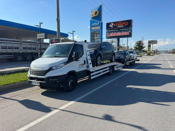 Yol uzerinde emniyet kemerleri ile sabitlenmis araclari tasiyan oto kurtarma araci