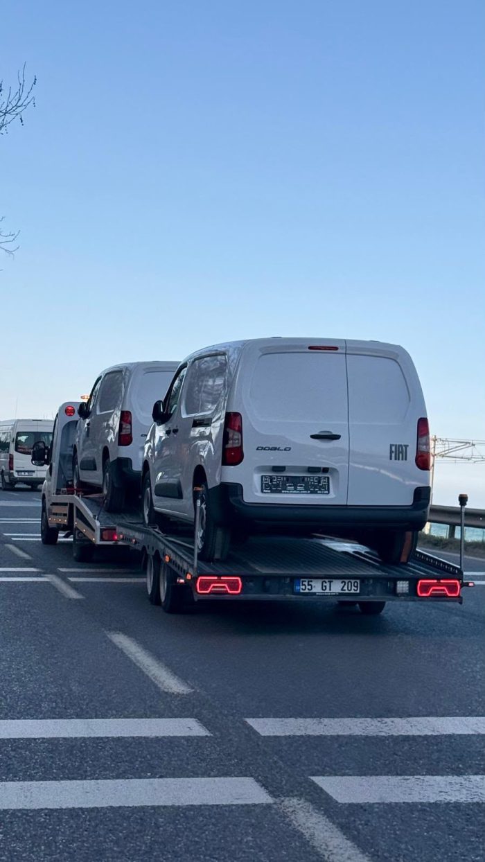 Sahil yolunda sifir kilometre ticari araclari tasiyan cekici ve romork